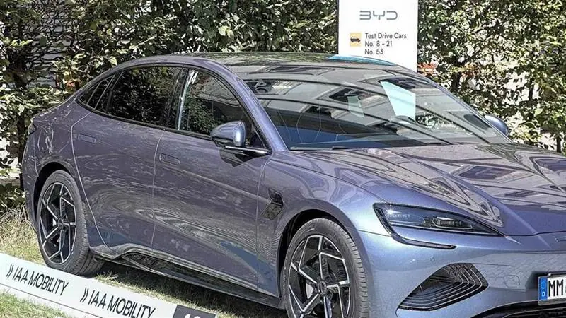 Grey BYD Seal electric sedan on display at the IAA Mobility show with a BYD test-drive sign in the background