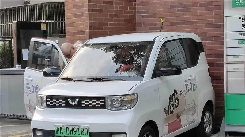 A white Wuling Hongguang Mini EV parked at a charging point in China.