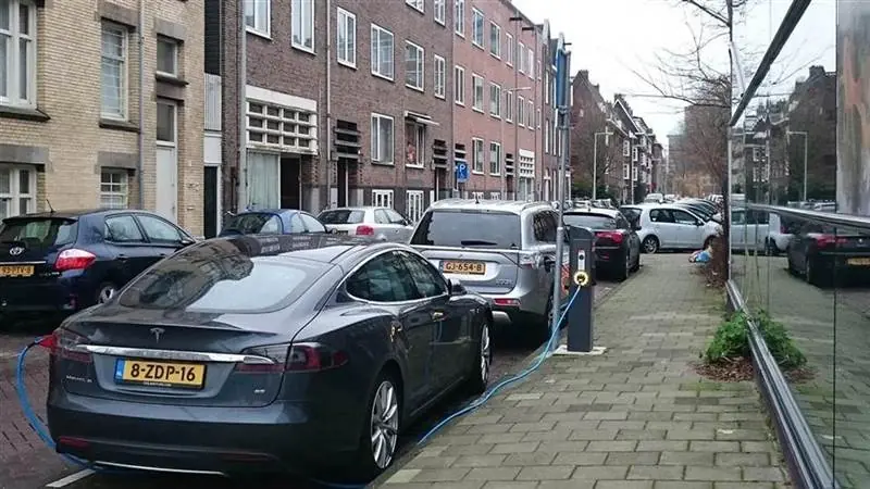 Electric cars parked at a curbside charging station on a canal-side street in Amsterdam