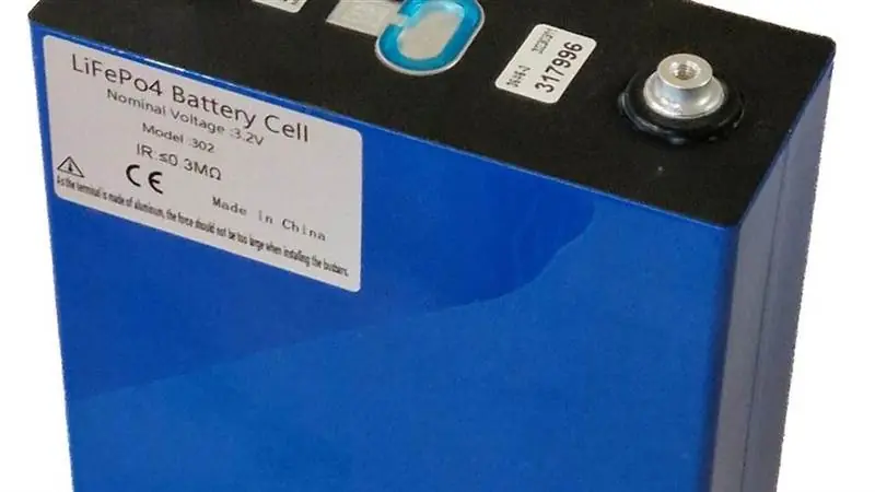 Close-up of a blue prismatic lithium iron phosphate battery cell with terminal posts and a specification label reading LiFePO4 Battery Cell