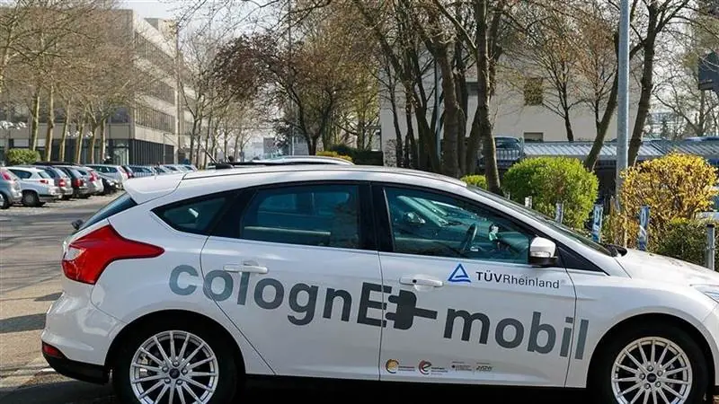 White electric car with colognE-mobil livery parked at an electric-car charging point in Cologne, Germany