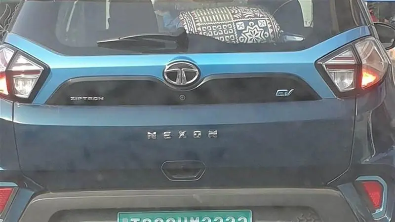 Rear view of a blue Tata Nexon EV electric SUV with Tata and EV badges and a green Indian electric-vehicle license plate, photographed in Hyderabad