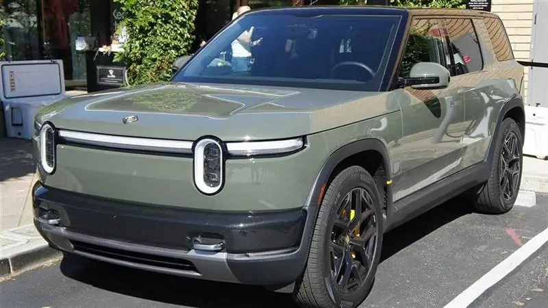 A Rivian R2 in Launch Green parked outside a Rivian showroom