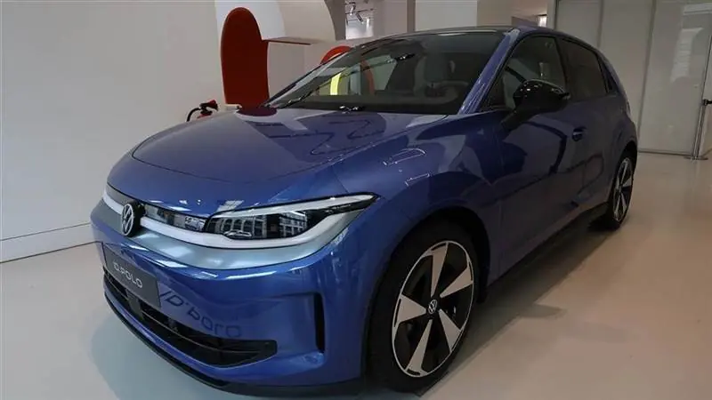 A blue production Volkswagen ID. Polo hatchback shown indoors in front three-quarter view, its ID. POLO badge visible on the front bumper