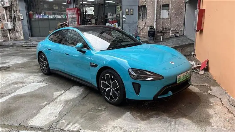 A blue Xiaomi SU7 electric sedan photographed from the front on a city street