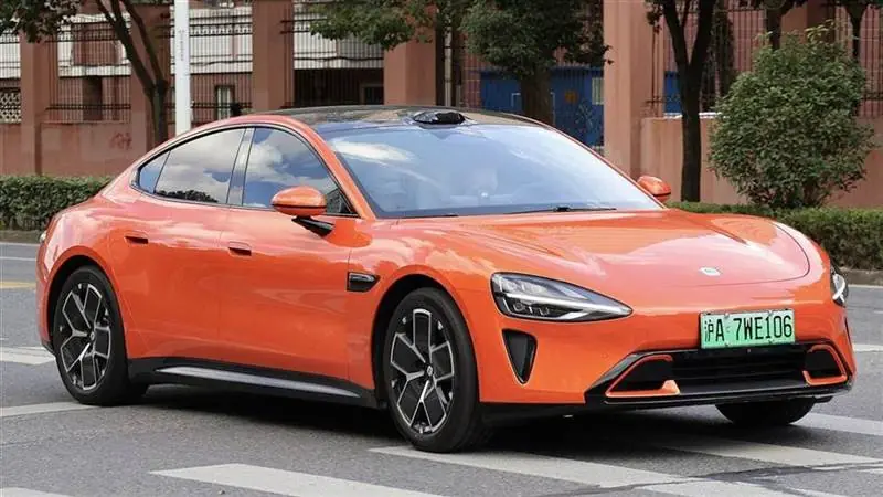 An orange Xiaomi SU7 electric sedan parked on a street in Shanghai, photographed in November 2024